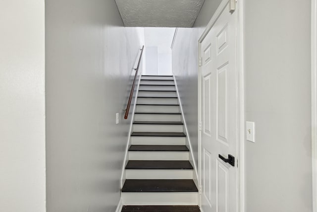 staircase featuring a textured ceiling