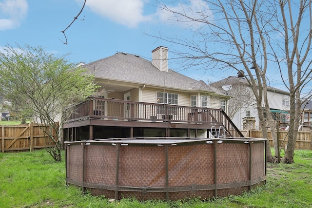 rear view of house with a fenced backyard, a fenced in pool, a chimney, and a wooden deck