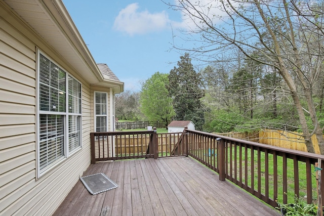 wooden terrace with a fenced backyard, a lawn, and an outbuilding
