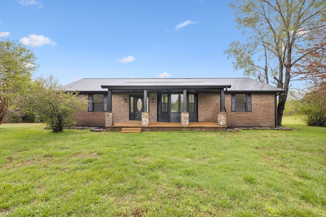 view of front of property with metal roof, a front yard, covered porch, and brick siding