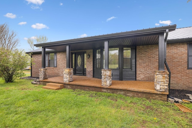 back of property with a lawn, metal roof, a porch, and brick siding
