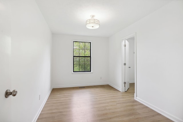 spare room featuring baseboards, visible vents, and light wood-style floors