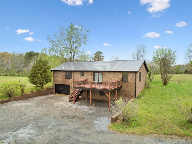 rear view of house with stairs, a garage, a lawn, a deck, and driveway