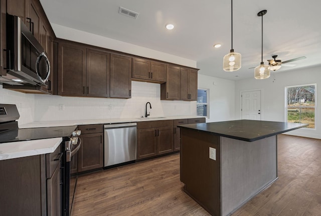 kitchen featuring visible vents, stainless steel appliances, dark brown cabinets, a sink, and dark wood-style floors