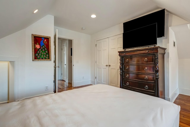 unfurnished bedroom featuring vaulted ceiling, a closet, wood finished floors, baseboards, and recessed lighting