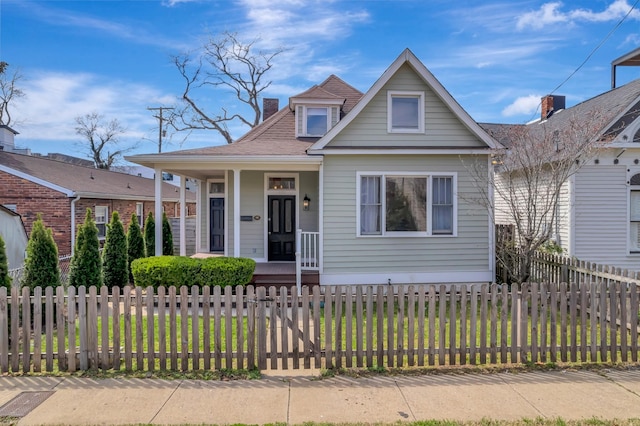 view of front facade with a chimney, a fenced front yard, a front yard, and a porch