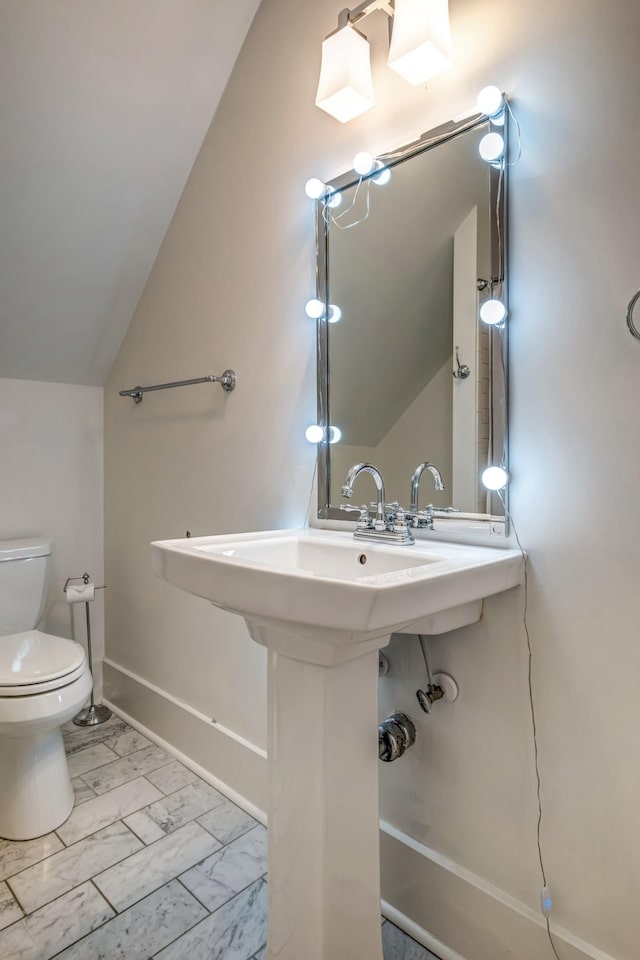bathroom with marble finish floor, baseboards, lofted ceiling, and toilet