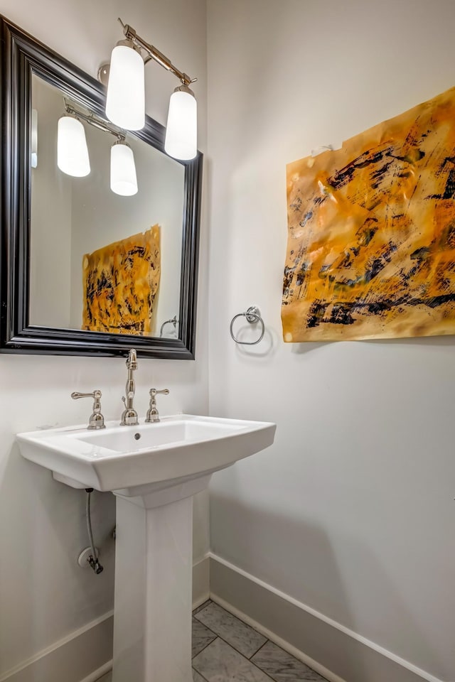 bathroom featuring baseboards, marble finish floor, and a sink