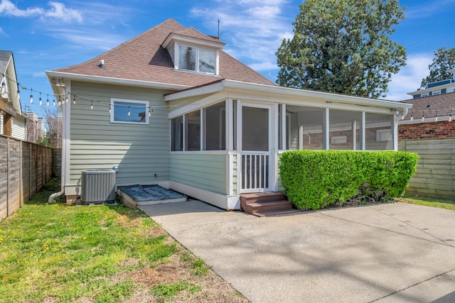 exterior space with cooling unit, a sunroom, fence, a shingled roof, and a yard