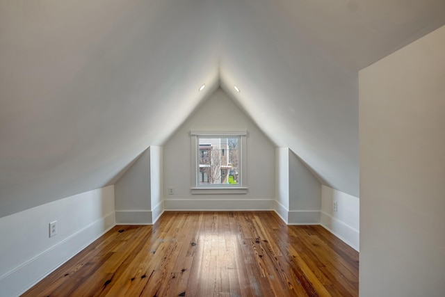 additional living space with hardwood / wood-style flooring, baseboards, and vaulted ceiling