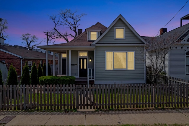 view of front of house featuring covered porch, a fenced front yard, and a chimney