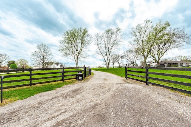 view of road with driveway, a gate, a gated entry, and a rural view