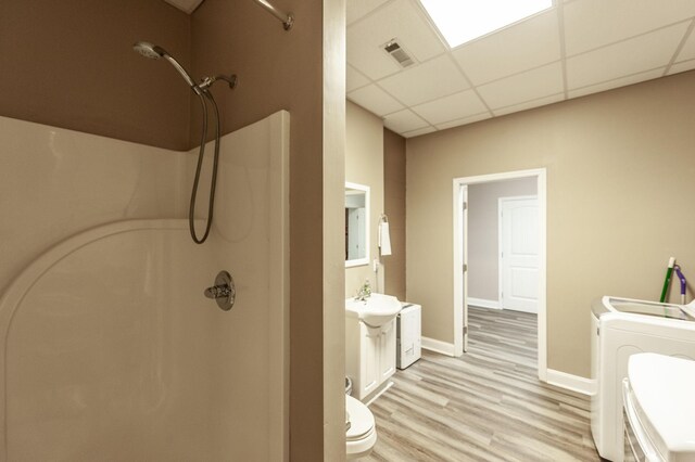 full bathroom featuring washer and clothes dryer, toilet, a shower, visible vents, and a drop ceiling