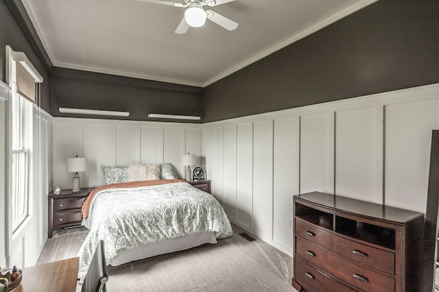 bedroom featuring a decorative wall, visible vents, ornamental molding, wainscoting, and light colored carpet