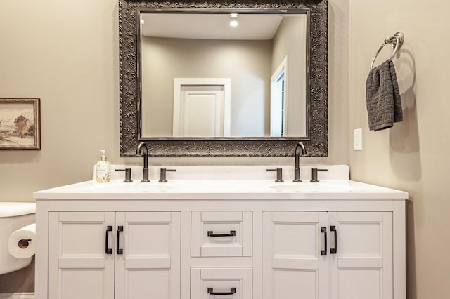 bathroom featuring double vanity, toilet, and a sink