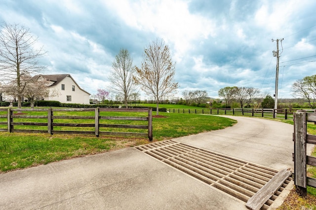 view of gate with a lawn, fence, and a rural view