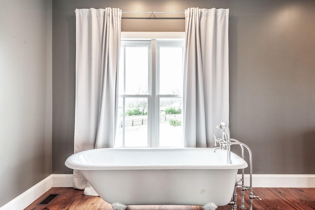 bathroom with a freestanding bath, baseboards, and wood finished floors