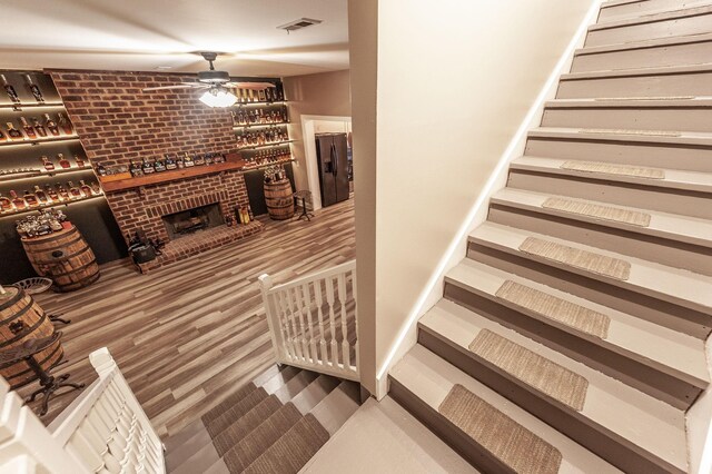 stairway with wood finished floors and a ceiling fan