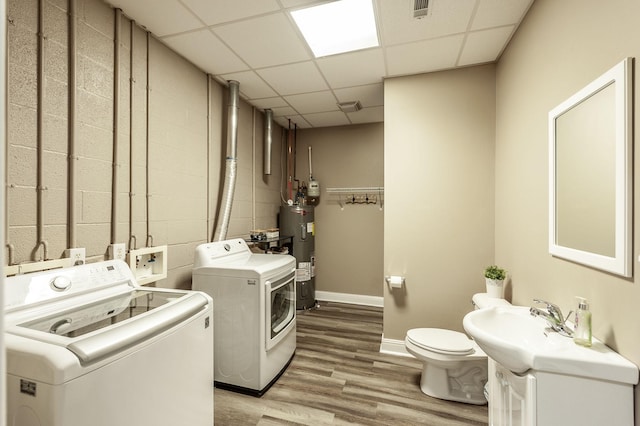 clothes washing area with water heater, light wood-style floors, baseboards, and washer and dryer