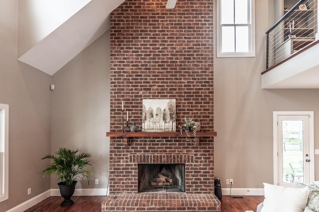 living area with a wealth of natural light, wood finished floors, and a towering ceiling