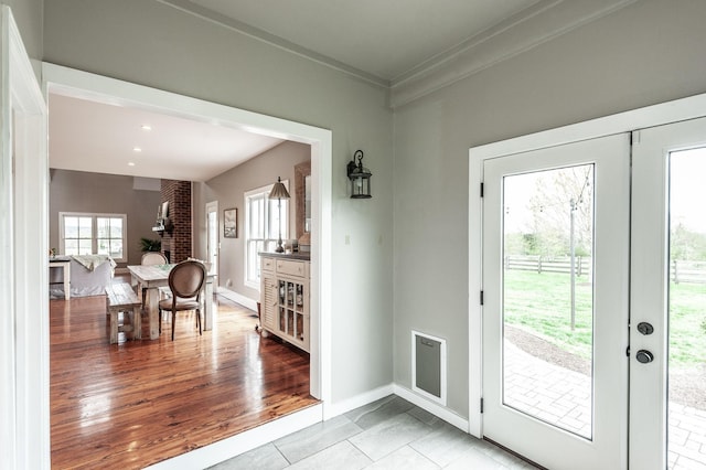 doorway to outside featuring visible vents, baseboards, ornamental molding, light wood-style floors, and french doors
