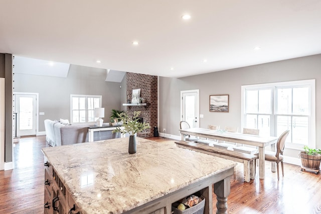 kitchen featuring a brick fireplace, light stone counters, light wood finished floors, and recessed lighting