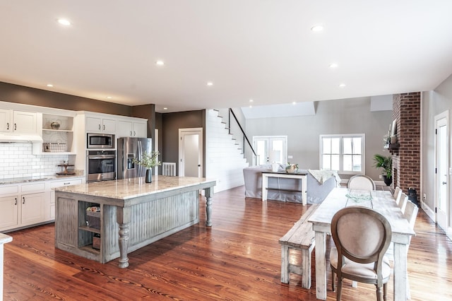 kitchen with a kitchen island, open shelves, appliances with stainless steel finishes, under cabinet range hood, and white cabinets