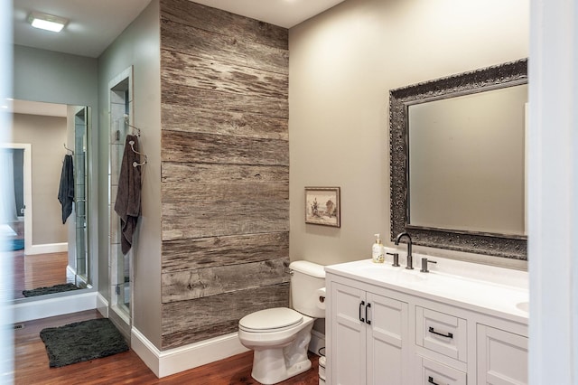 bathroom featuring a stall shower, toilet, wood walls, and a sink