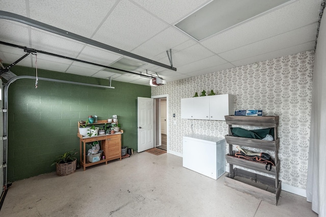garage featuring a garage door opener, wallpapered walls, and concrete block wall