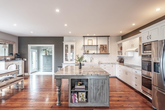 kitchen with decorative backsplash, white cabinets, stainless steel appliances, and open shelves