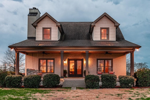 view of front facade featuring covered porch, a chimney, brick siding, and a ceiling fan