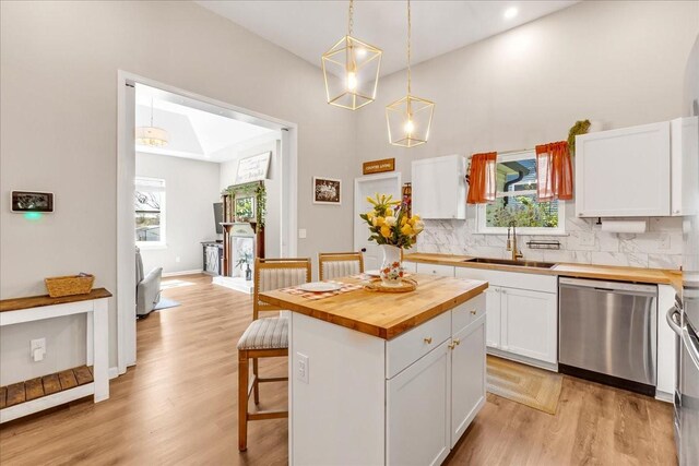 kitchen with butcher block counters, stainless steel dishwasher, white cabinetry, and a sink