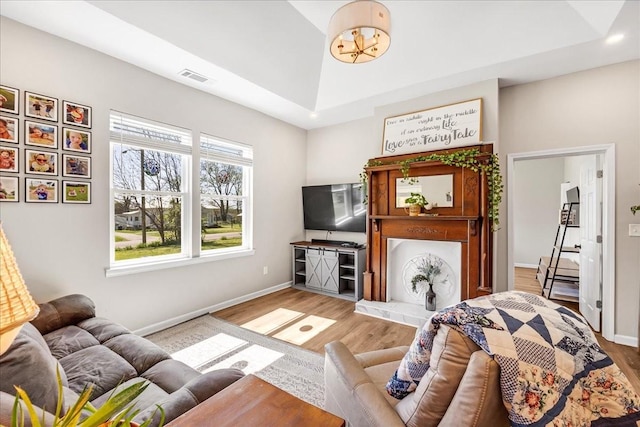 living area with visible vents, baseboards, and wood finished floors