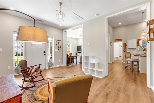 living room featuring light wood-type flooring, baseboards, and visible vents