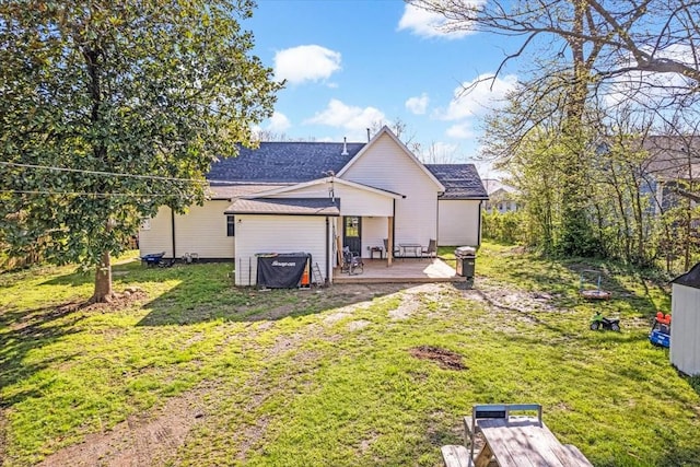 back of property featuring roof with shingles, a yard, and a deck