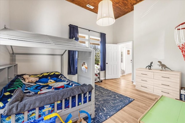 bedroom featuring visible vents, wooden ceiling, a high ceiling, and wood finished floors