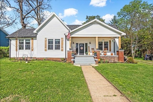 view of front facade with roof with shingles, a porch, and a front lawn