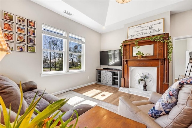 living area featuring wood finished floors, baseboards, and visible vents