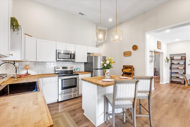 kitchen featuring wooden counters, light wood-style floors, visible vents, a breakfast bar area, and stainless steel appliances