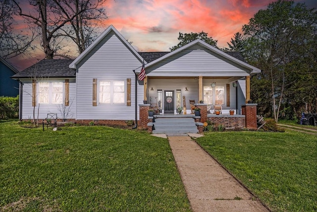 bungalow-style home with a porch, a shingled roof, and a front lawn
