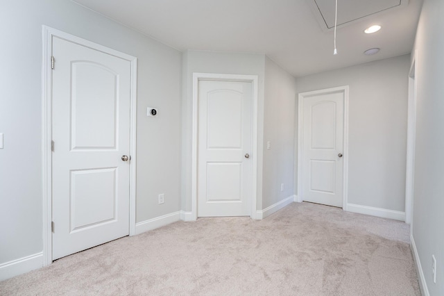 unfurnished room featuring baseboards, carpet, and attic access