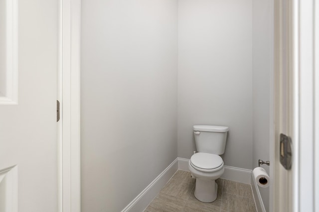 bathroom with baseboards, toilet, and tile patterned flooring