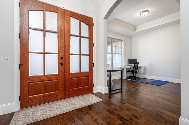 foyer with a tray ceiling, dark wood finished floors, baseboards, arched walkways, and ornamental molding