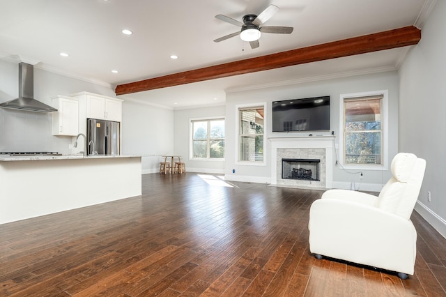 living area featuring a ceiling fan, beam ceiling, baseboards, and dark wood-type flooring