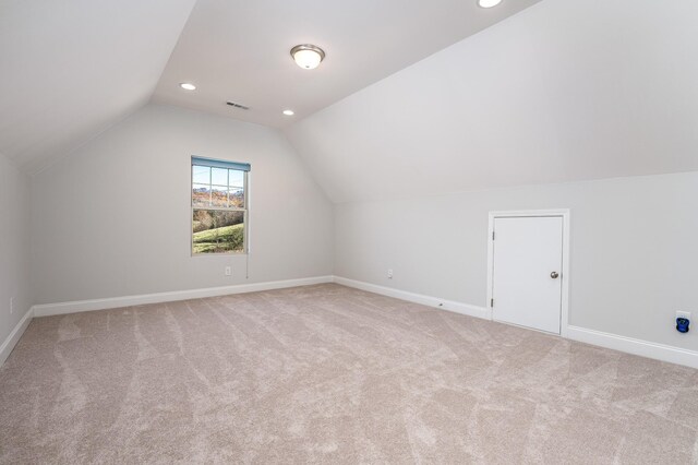 additional living space featuring baseboards, lofted ceiling, visible vents, and carpet