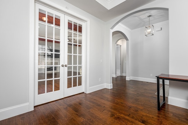 unfurnished room featuring baseboards, arched walkways, french doors, and hardwood / wood-style floors