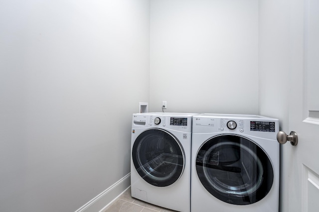 washroom featuring washer and clothes dryer, laundry area, baseboards, and light tile patterned floors