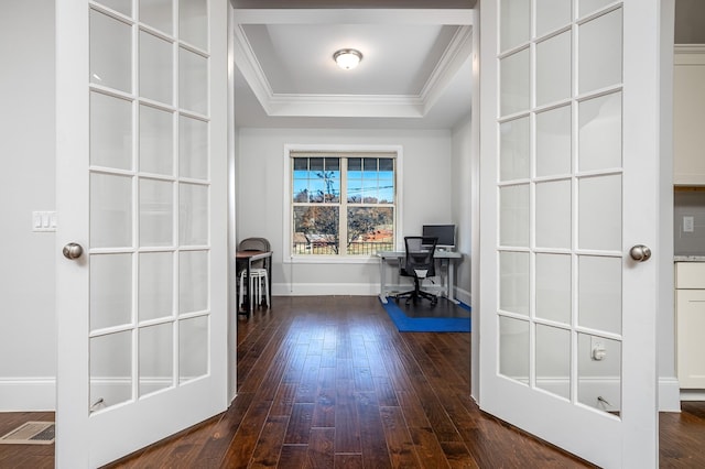 unfurnished office featuring visible vents, baseboards, ornamental molding, dark wood finished floors, and a tray ceiling