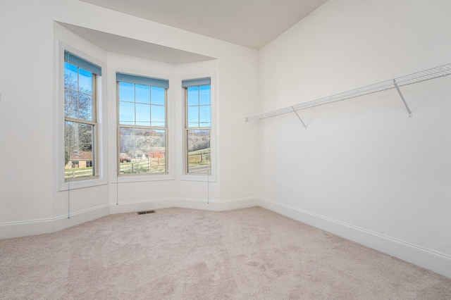 empty room with carpet floors, baseboards, and visible vents