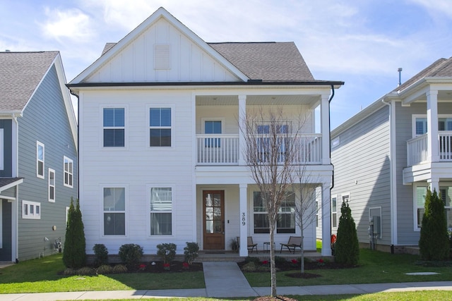 view of front of property with board and batten siding, a balcony, a front lawn, covered porch, and a shingled roof